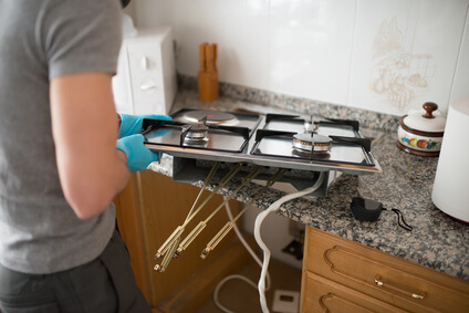  Man installing a gas hob in a kitchen.